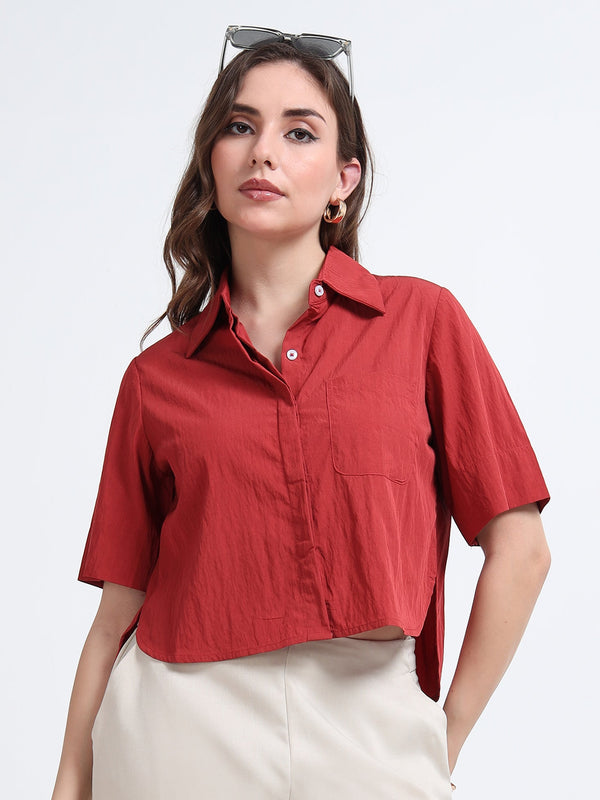 Woman wearing a red shirt and white pants on a light gray background